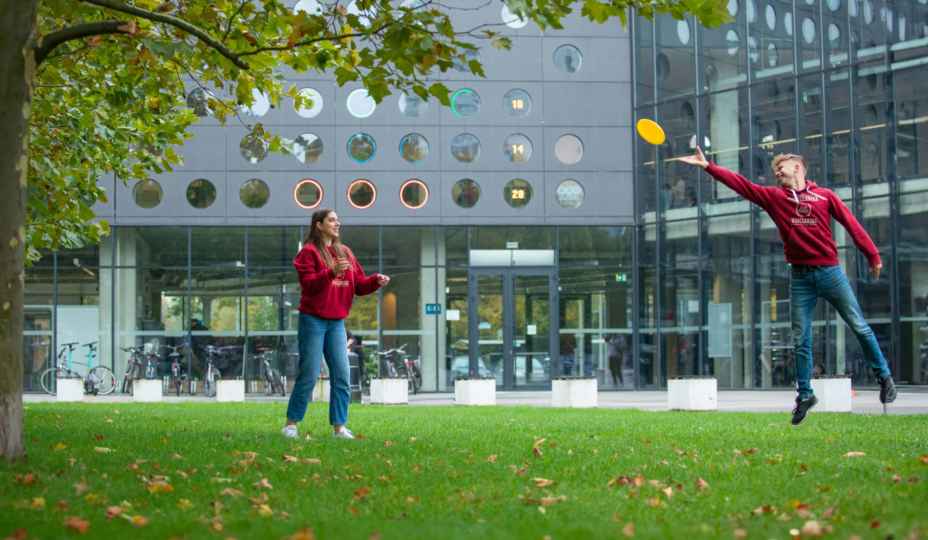 Zdjęcie studentów rzucających frisbee na kampusie