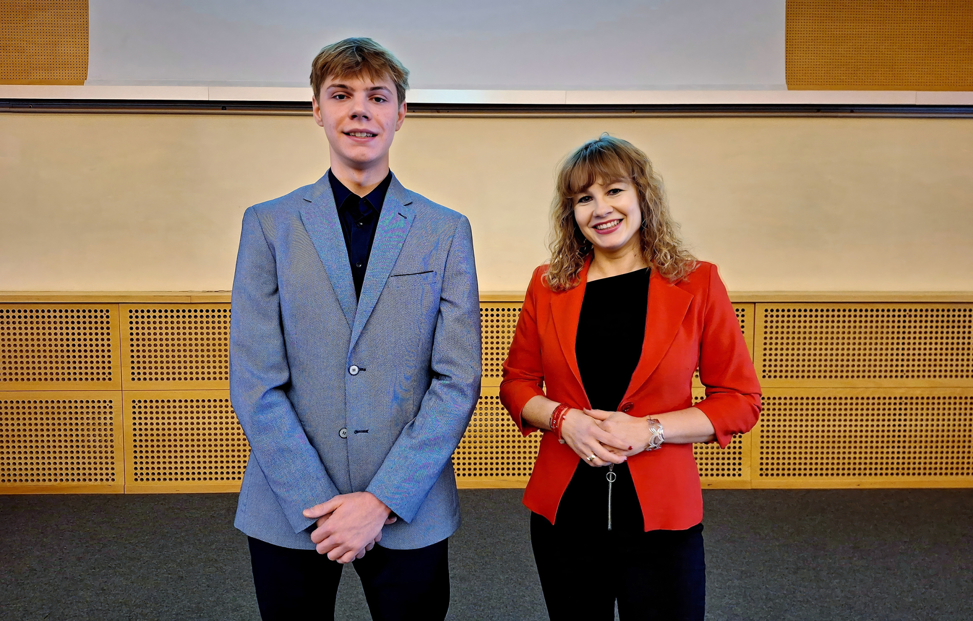 Pięć osób w eleganckich strojach stoi w rzędzie w sali wykładowej Politechniki Wrocławskiej, pozując do wspólnego zdjęcia.