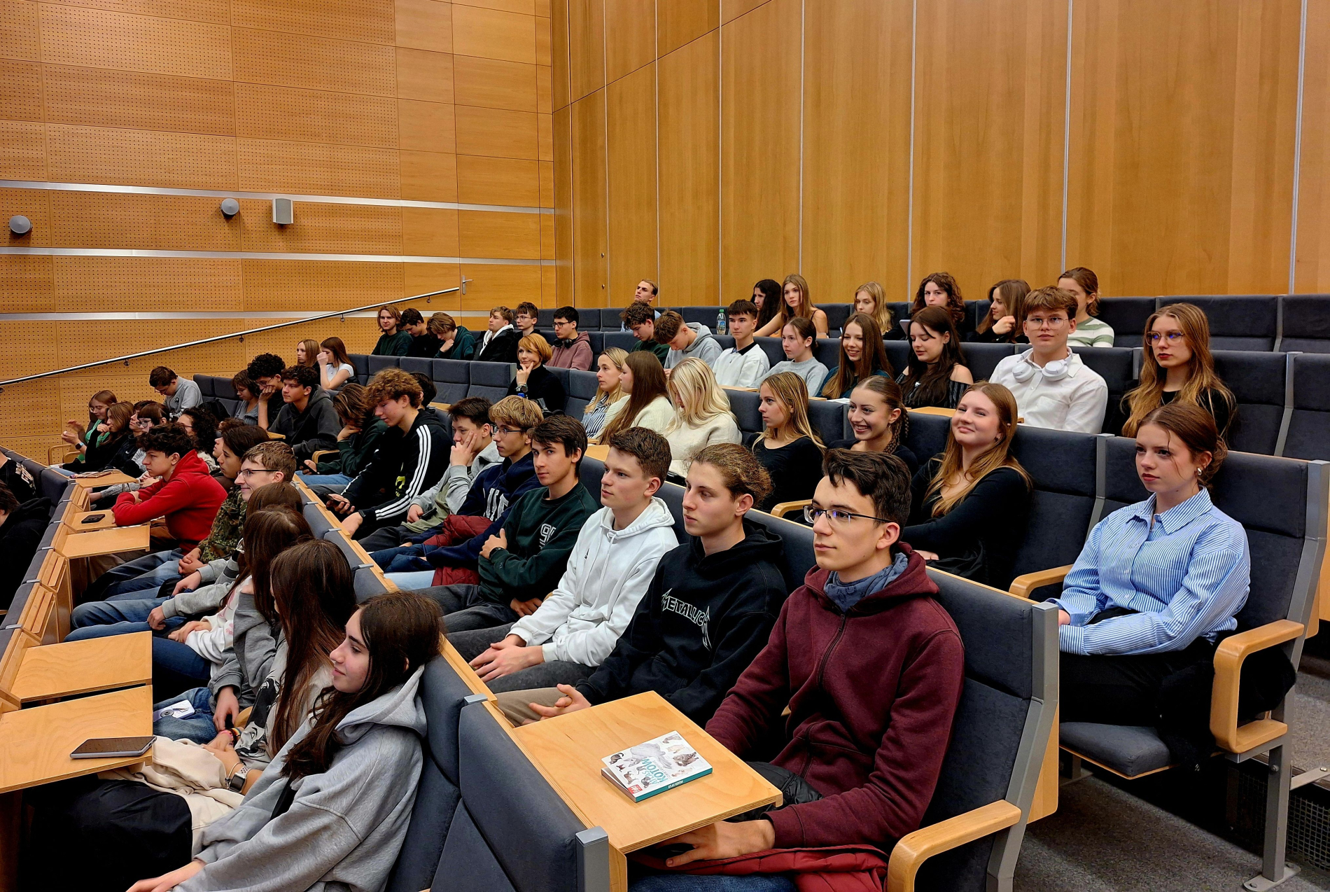 Grupa młodych osób siedzi w auli, uważnie słuchając prezentacji na Politechnice Wrocławskiej.