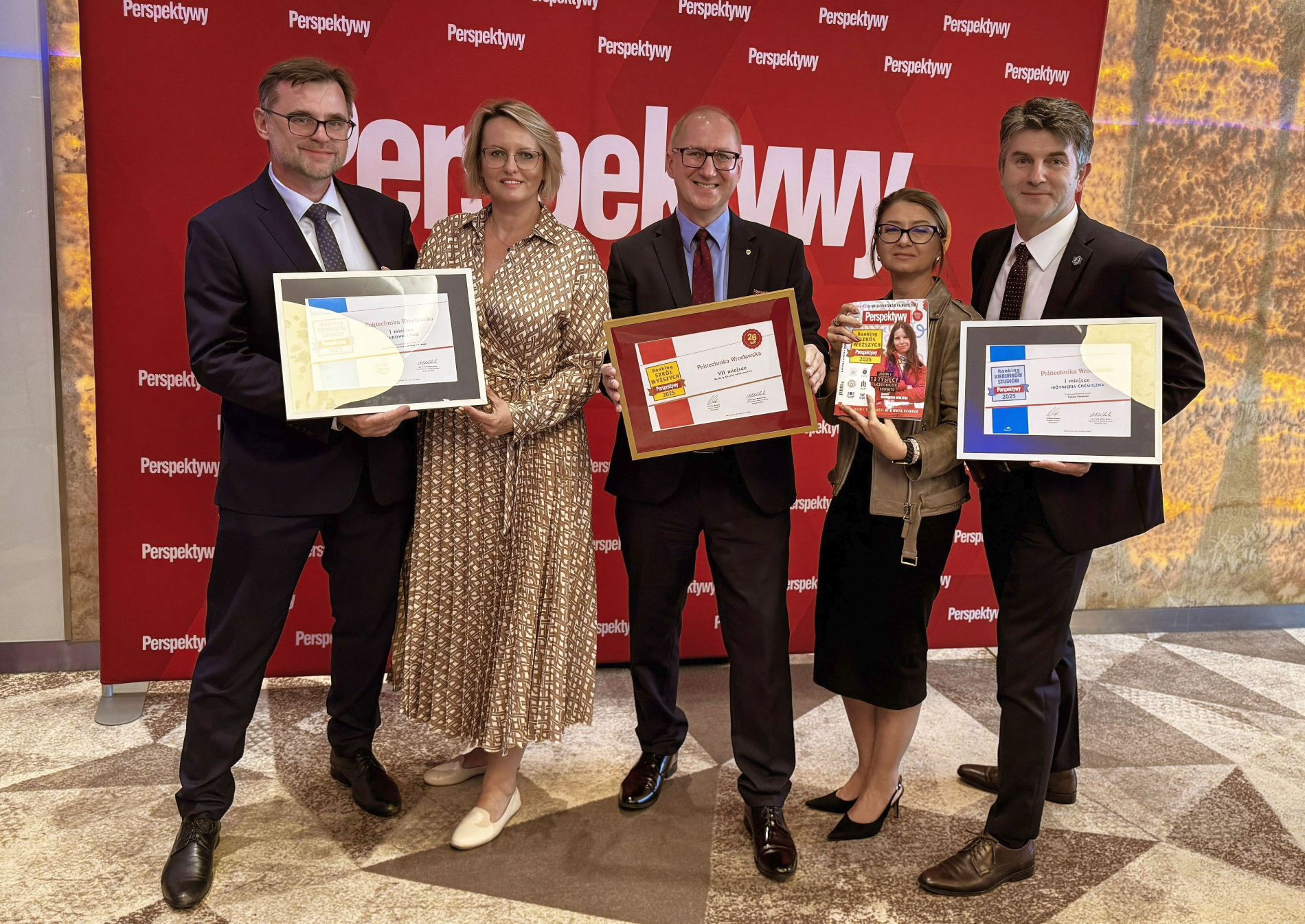 Pięcioro dorosłych osób stoi przed ścianką z logo „Perspektywy”. Trzymają dyplomy i nagrody. Zdjęcie przedstawia nagrody dla Politechniki Wrocławskiej w Rankingu Kierunków Studiów Perspektywy 2025.