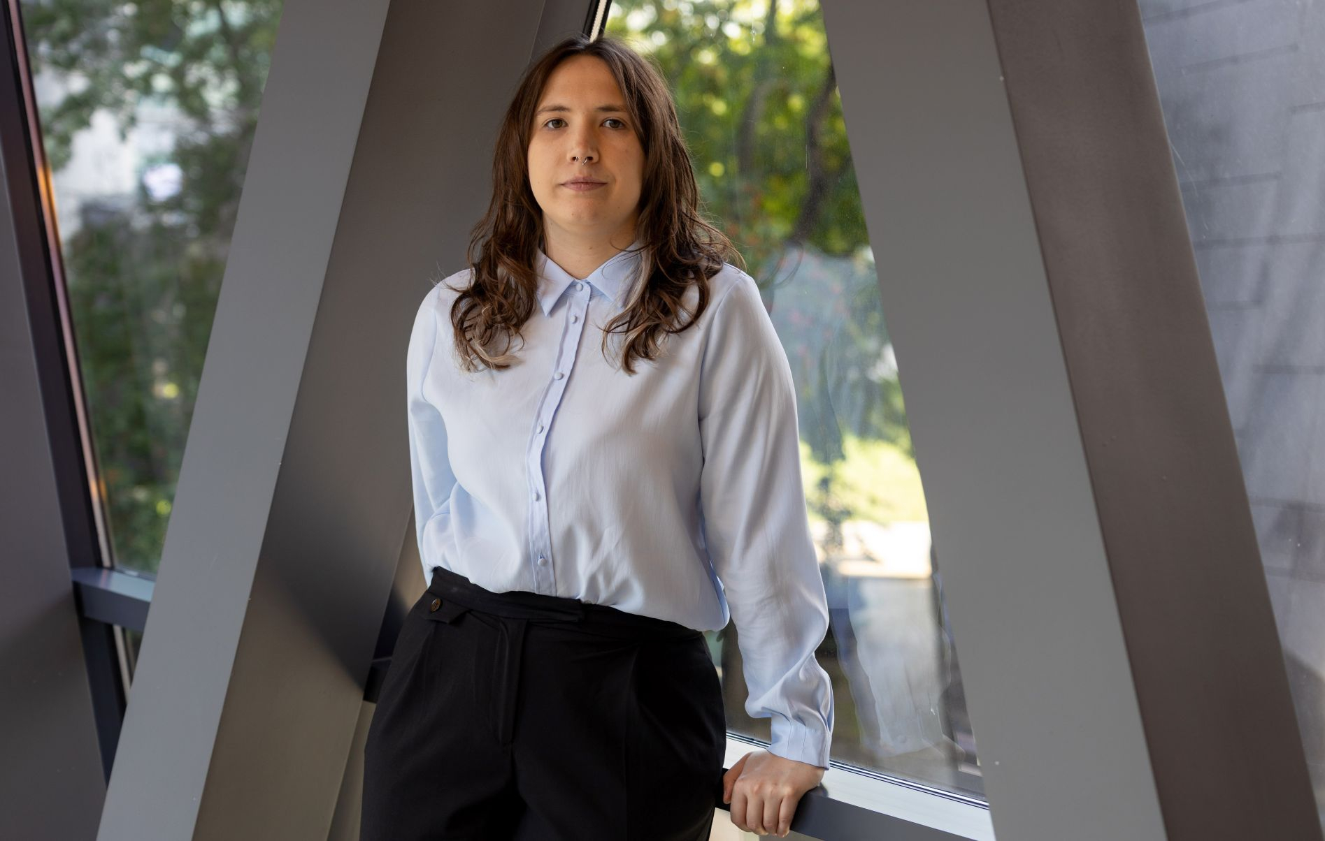 Zdjęcie kobiety w niebieskiej koszuli stojącej w korytarzu budynku Politechniki Wrocławskiej