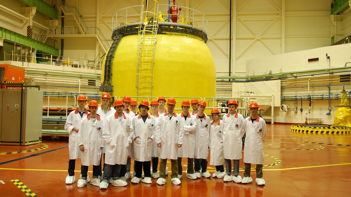 Zdjęcie grupy osób w strojach laboratoryjnych i kaskach