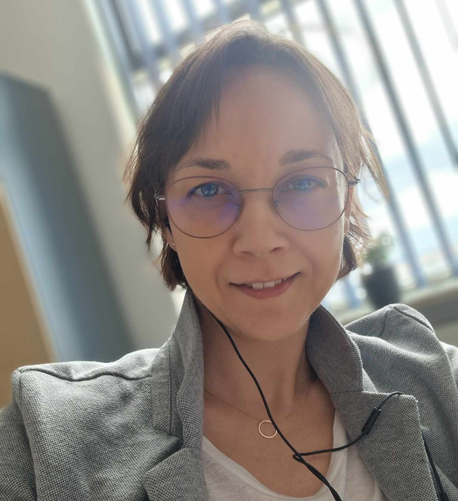 opis alt Niestandardowy Gem  Analiza joanna_budzisz_pwr.jpg Portret uśmiechniętej kobiety w okularach i szarej marynarce. Ma brązowe, krótkie włosy i słuchawki douszne. Tło jest jasne i rozmyte.
