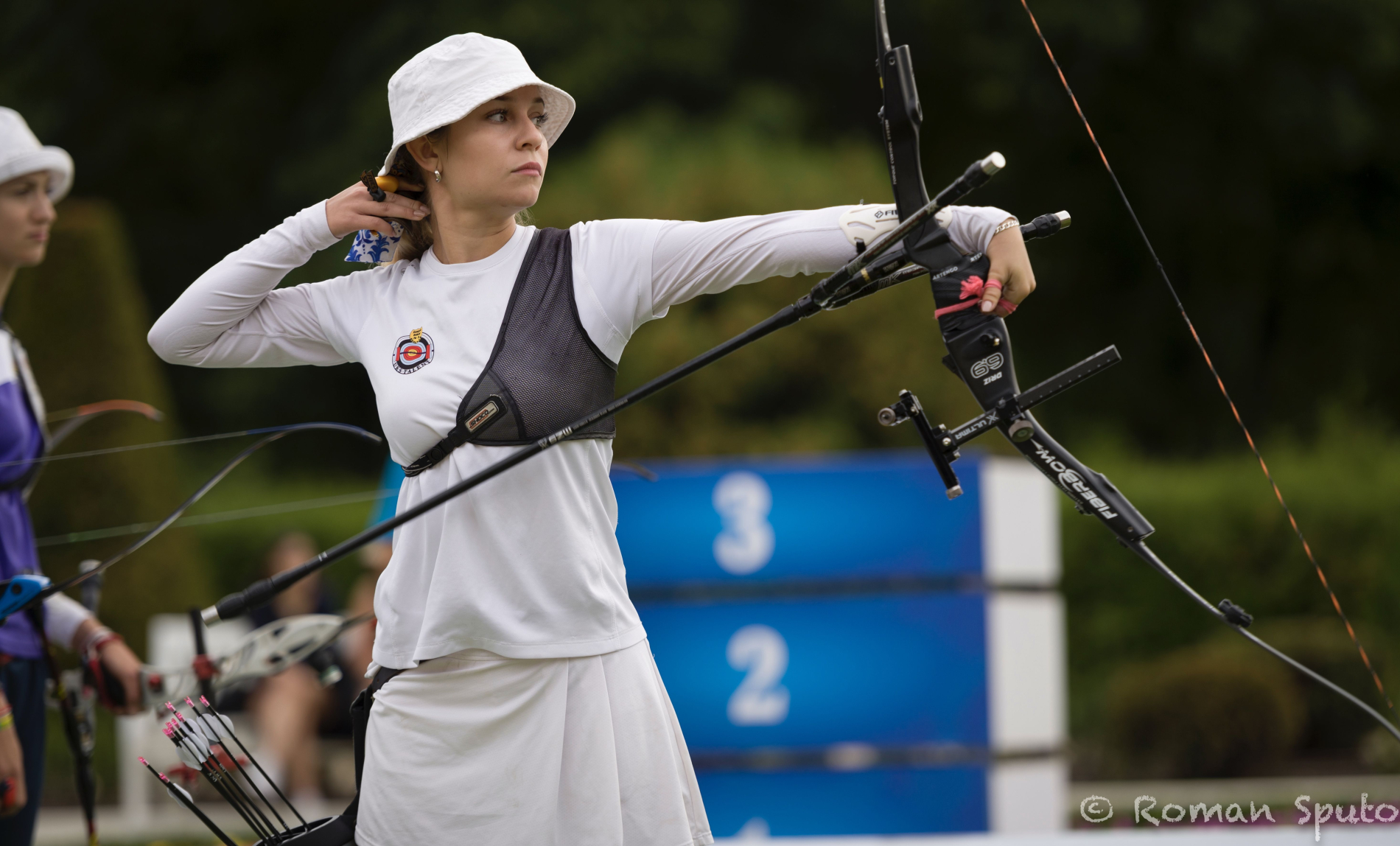 Zdjęcie dziewczyny w białym stroju sportowym strzelającej z łuku