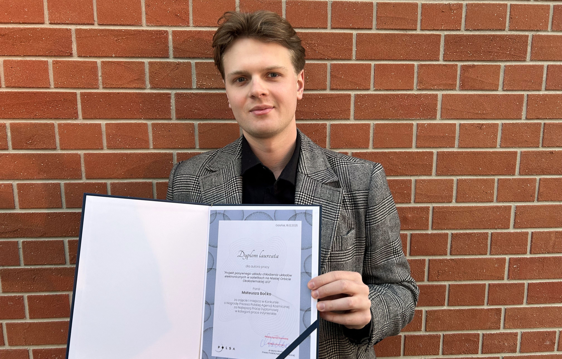 Zdjęcie Matuesza Boćko trzymającego otwarty dyplom z nagrodą