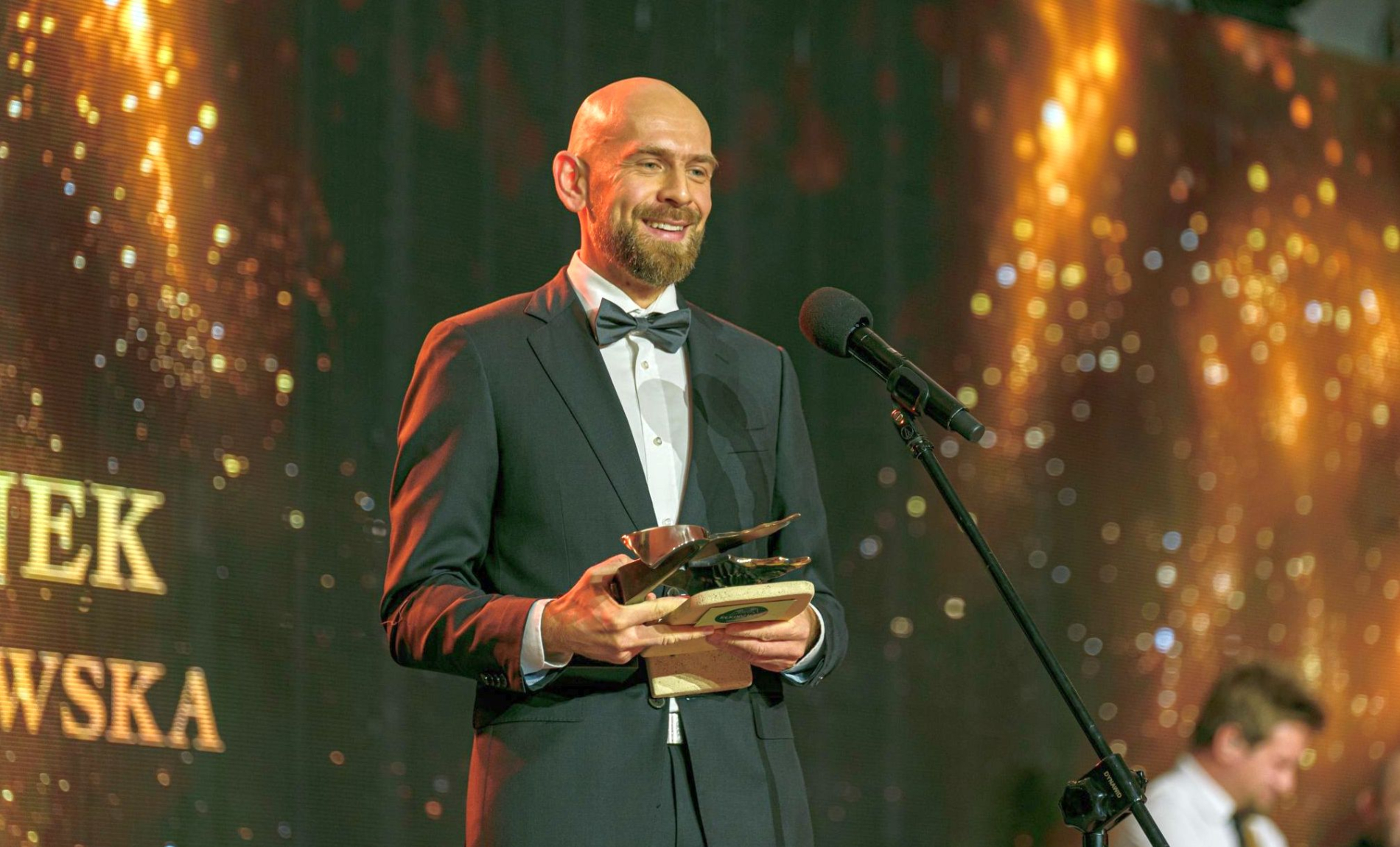 Zdjęcie dr. Michała Panka z dyplomem i nagrodą na scenie