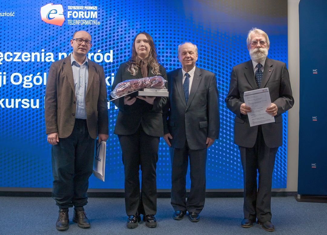 Zdjęcie czterech osób stojących obok siebie, kobieta trzyma dyplom i nagrodę.