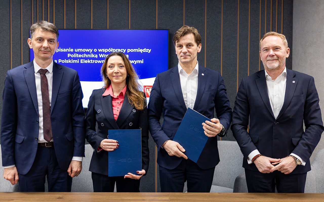 Zdjęcie czwórki osób stojących obok siebie, dwie trzymają podpisane umowy