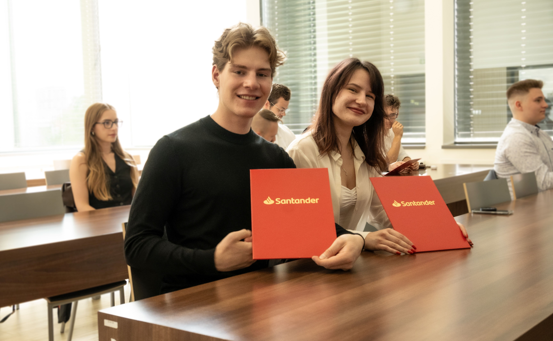 Zdjęcie dwóch osób trzymających czerwone dyplomy z napisem Nagroda Santander