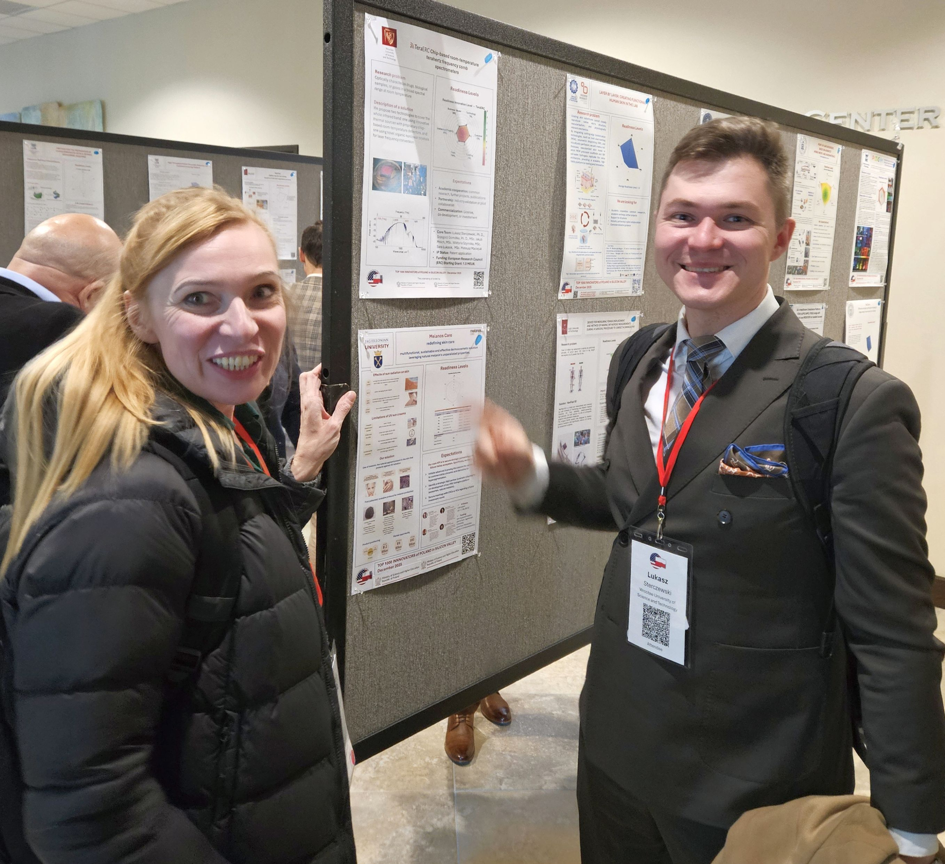 Zdjęcie dwóch osób stojących przy posterze naukowym