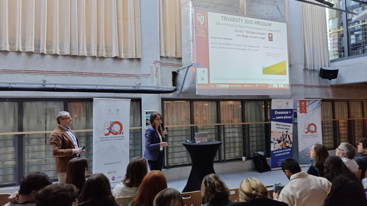 Prelegentka w niebieskiej marynarce przemawia na tle slajdu "TriVarsity 2025 Wrocław".