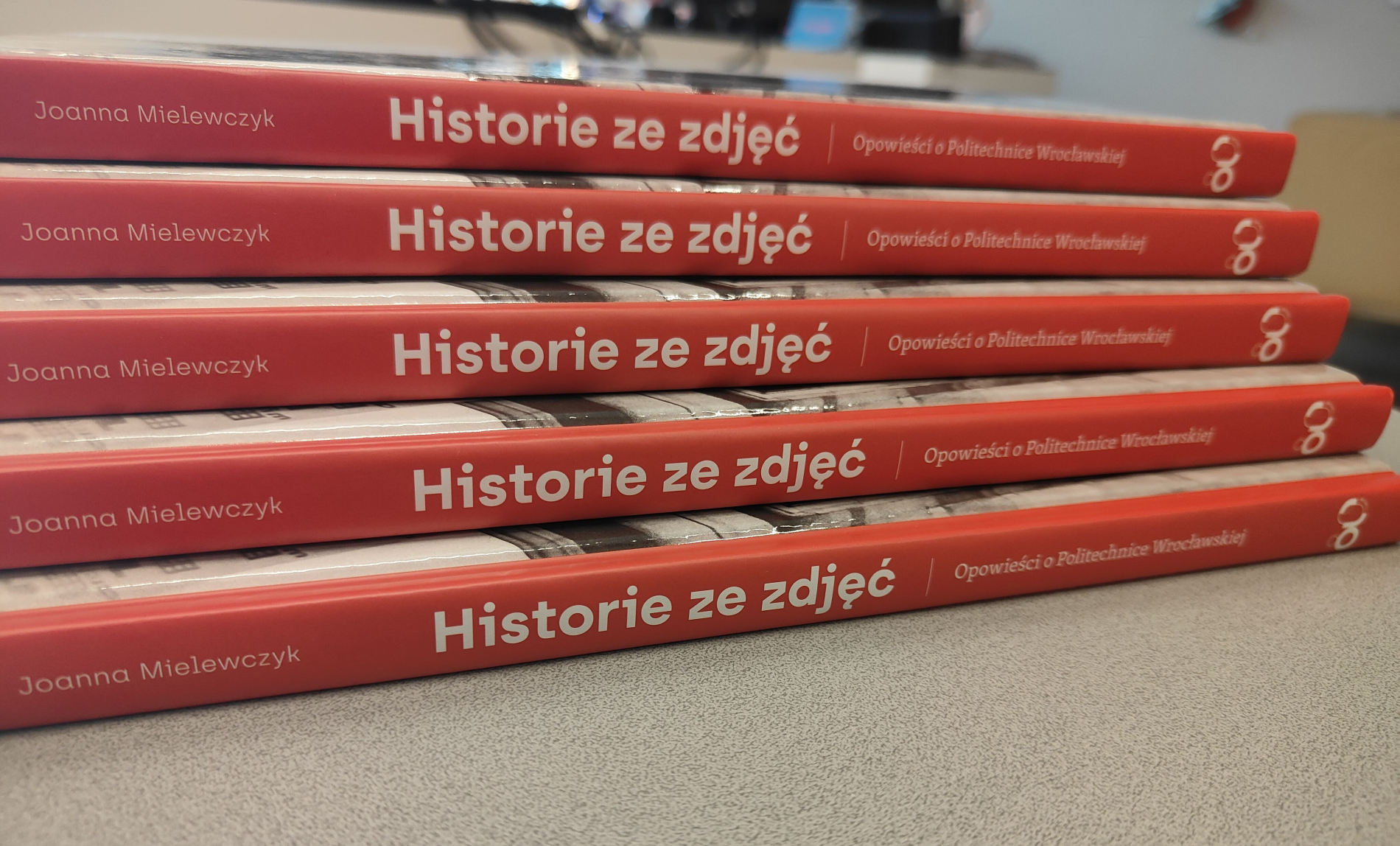 Zbiorowe ujęcie z bliska na pięć ułożonych w stos, czerwonych grzbietów książek "Historie ze zdjęć".