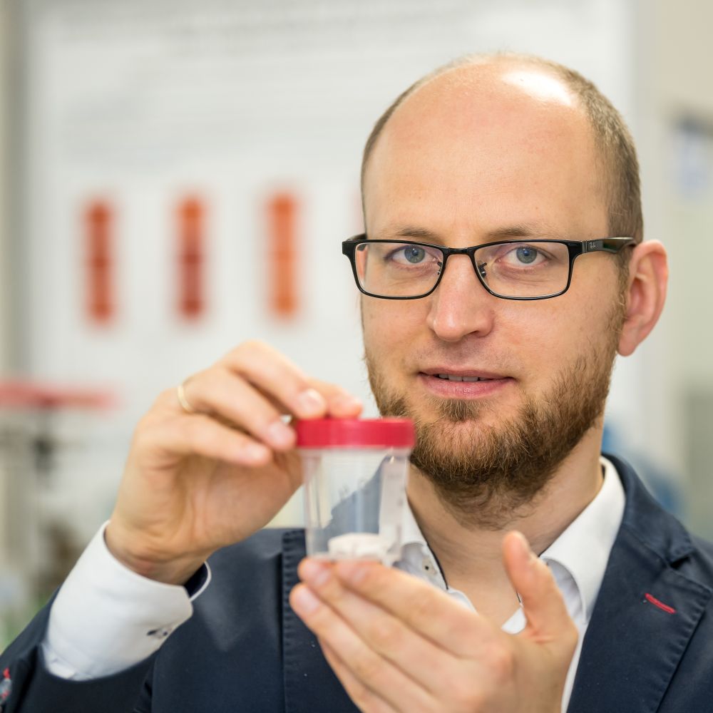 prof. Konrad Szustakiewicz z Katedry Inżynierii i Technologii Polimerów trzyma pojemnik z biokompozytem w formie gąbki