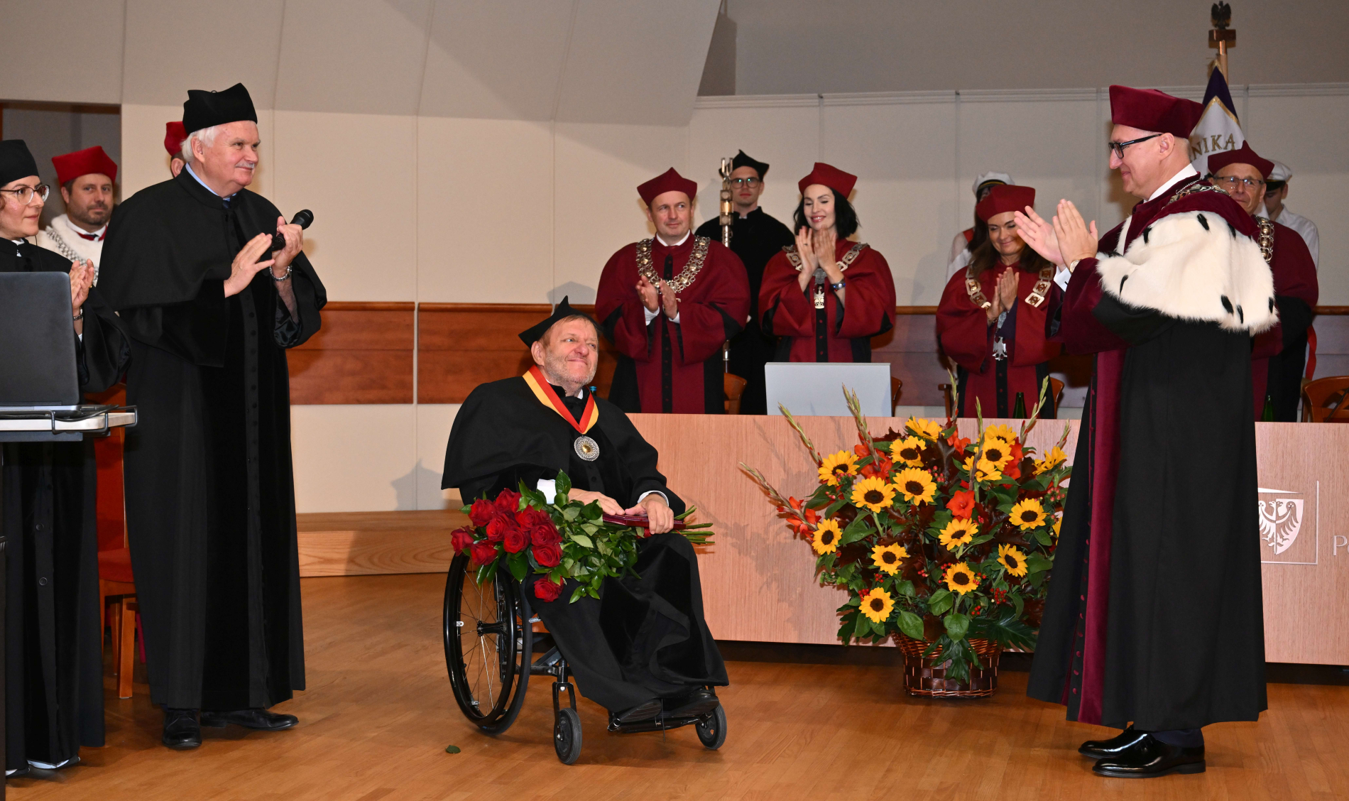 Zdjęcie osoby na wózku inwalidzkim odbierającej medal na auli PWr