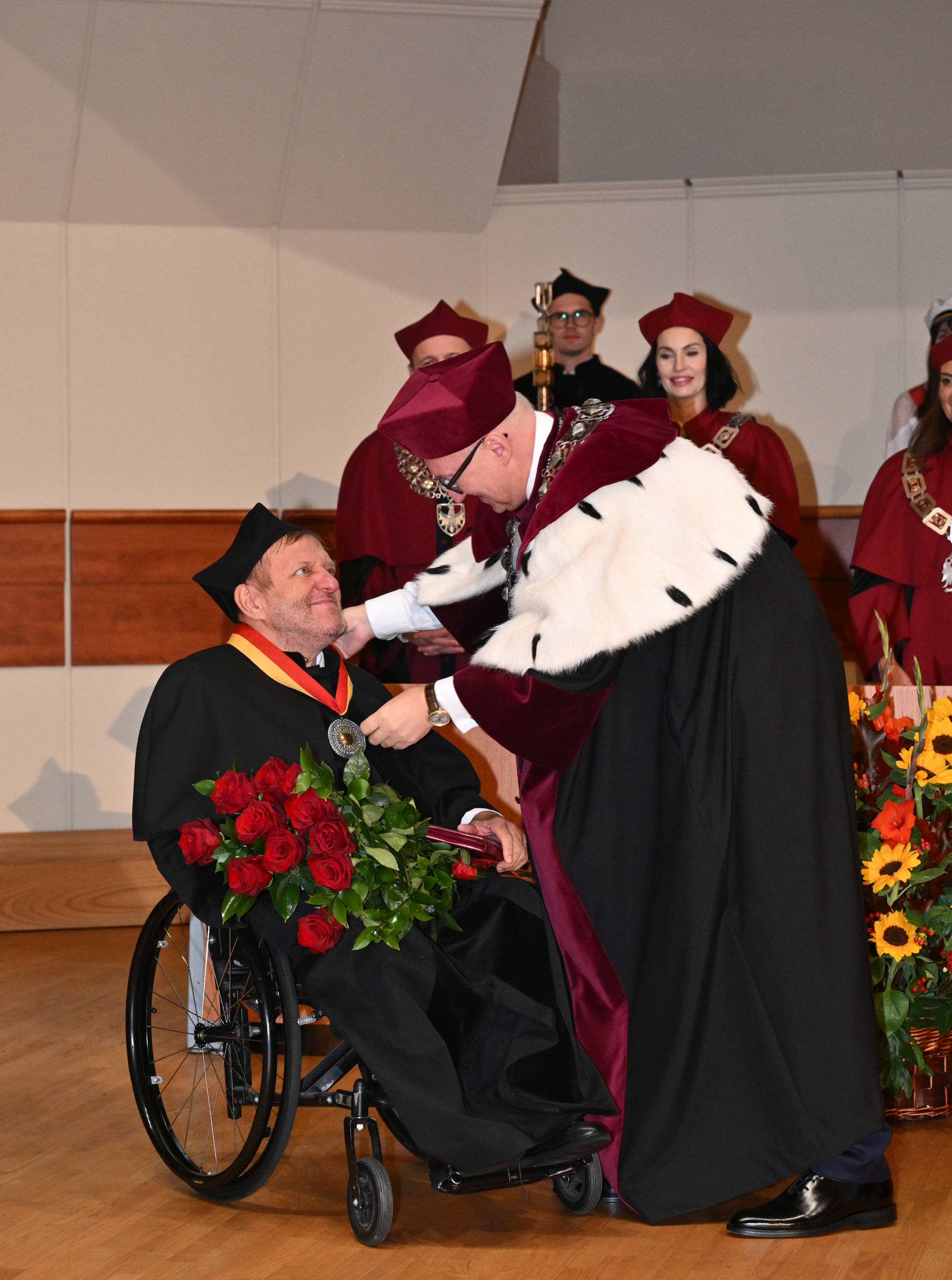 Zdjęcie osoby na wózku inwalidzkim odbierającej medal na auli PWr