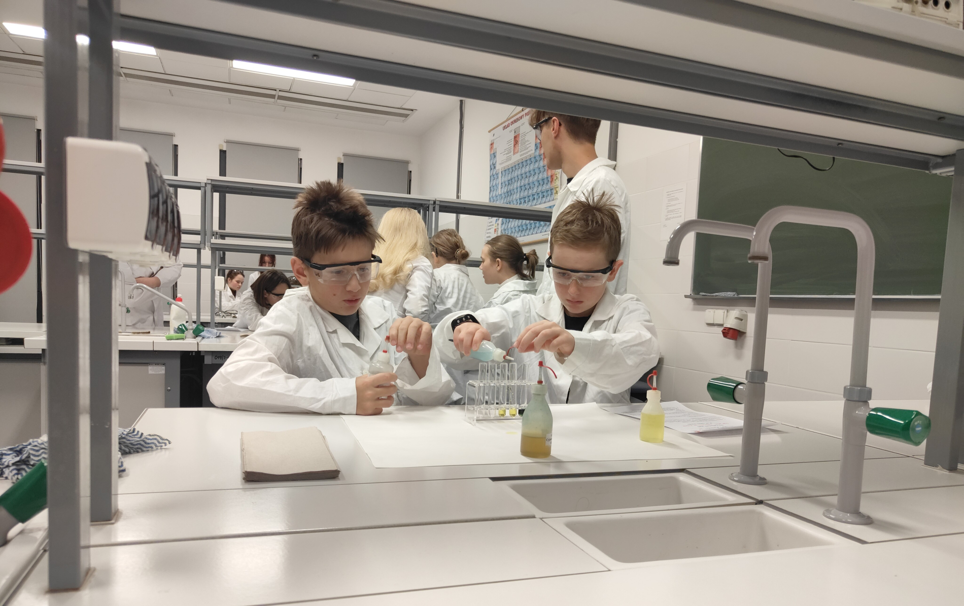 Dwóch chłopców w fartuchach w laboratorium chemicznym