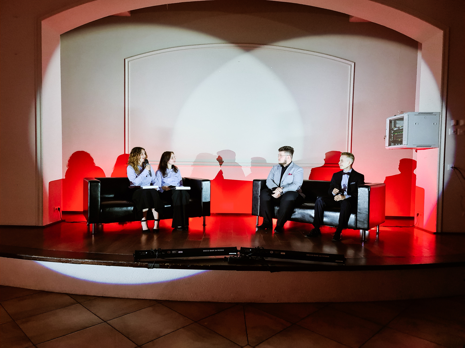 Cztery osoby siedzę na kanapach na scenie i rozmawiają
