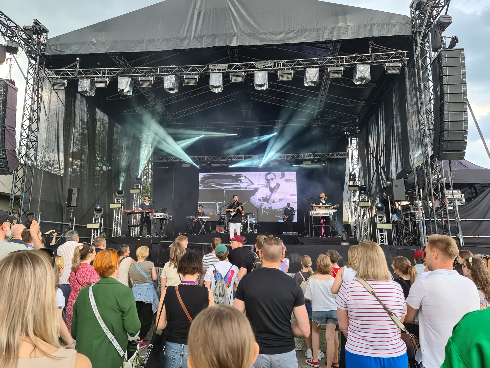 Zdjęcie osoby śpiewającej na scenie do ludzi na bulwarze