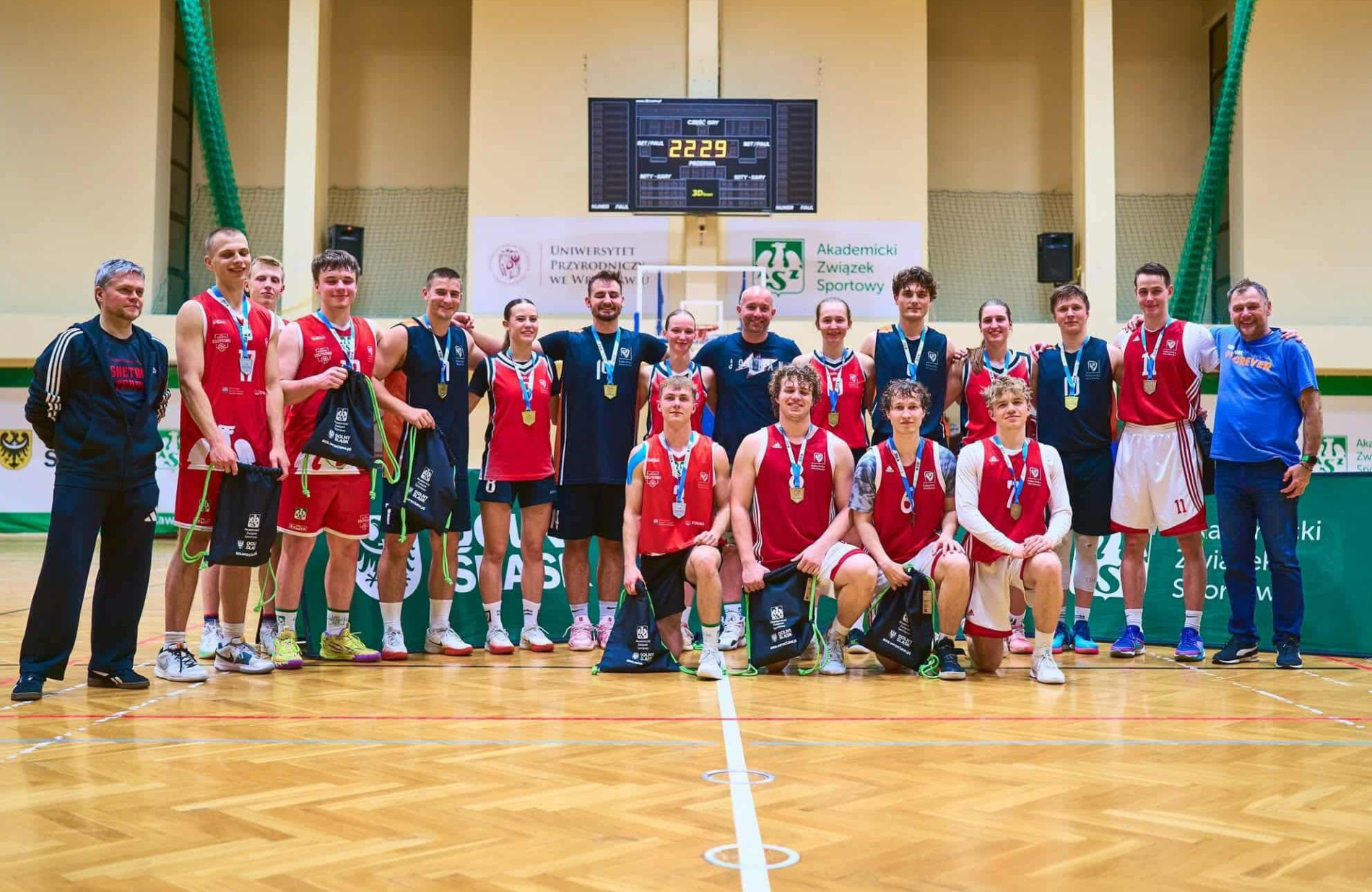 Zdjęcie grupowe koszykarzy i koszykarek PWr z medalami w hali Uniwersytetu Przyrodniczego