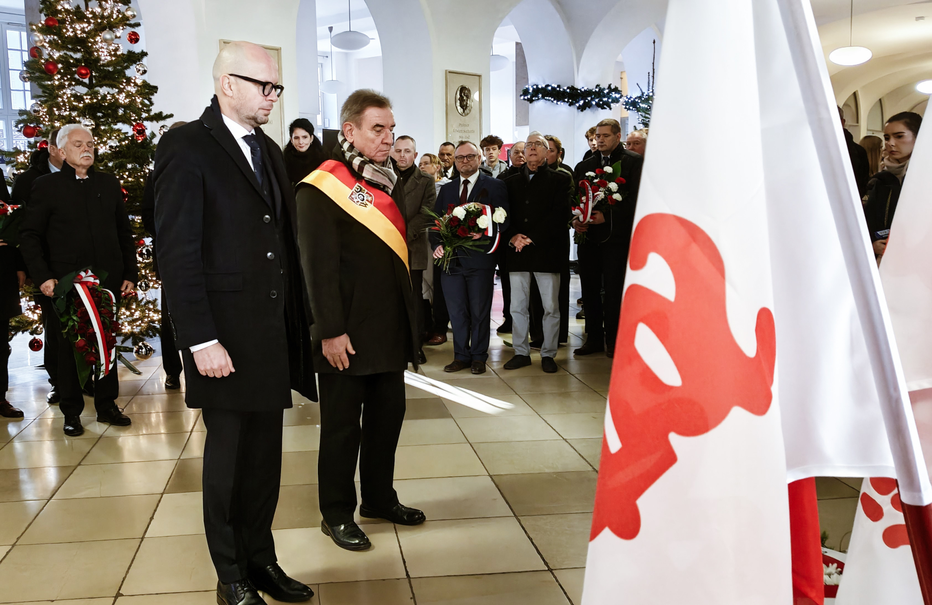 Zdjęcie dwóch osób stojących w holu PWr przed tablicą.