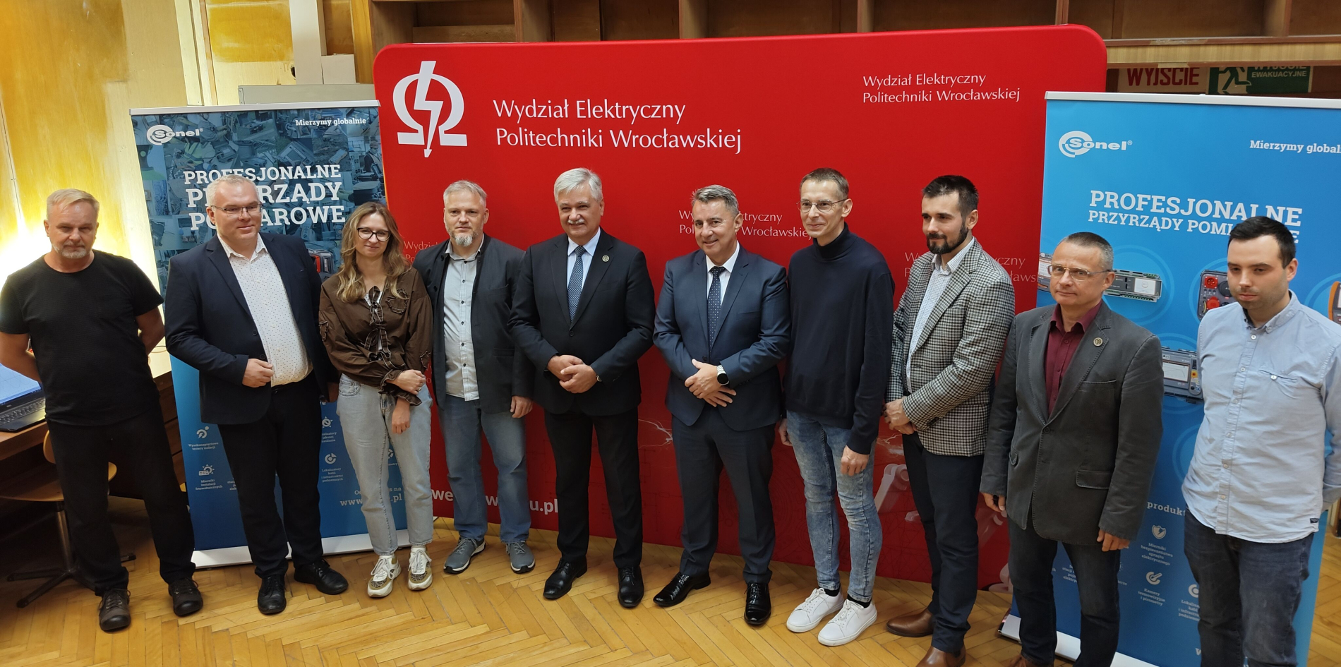 Stanowisko laboratoryjne do badań mikrosieci: na kratownicy wiszącej nad stołem widoczny jest inwerter fotowoltaiczny i mierniki.